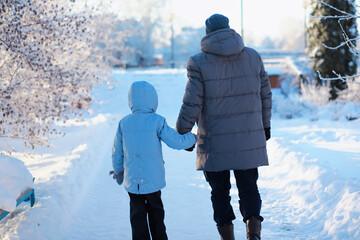 Wall Mural - Family with children play snowy winter games in the park. Winter holidays and family vacation. Winter walk on the street on a sunny frosty day.