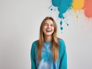 Portrait of teenager girl with splashes of paint on clothes and gray background