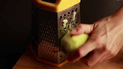 Wall Mural - Close up of woman grating a red apple with skin on large holes of box grater