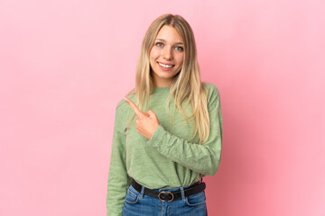 Poster - Young blonde woman isolated on pink background pointing to the side to present a product