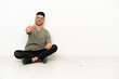 © luismolinero - Young caucasian man sitting on the floor isolated on white background showing and lifting a finger