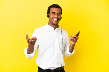 Canvas Print - African American Telemarketer man working with a headset over isolated yellow background keeping a conversation with the mobile phone with someone