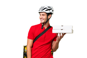 Wall Mural - Pizza delivery man with work uniform picking up pizza boxes over isolated background looking to the side and smiling