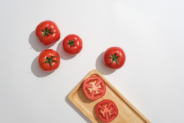 Wall Mural - Against a white background, fresh tomatoes decorated with wooden cutting board. Minimal scene for advertising. Eat a lot of tomatoes to help brighten the skin, anti-oxidant and prevent acne