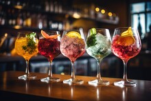 Variety Of Alcoholic Cocktails On The Bar Counter In Night Club, Five Colorful Gin Tonic Cocktails In Wine Glasses On The Bar Counter In A Pub Or Restaurant, AI Generated