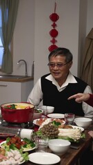 Wall Mural - Vertical Screen: Chinese grandfather waiting for serving hot pot on portable stove on table. happy family having reunion dinner on new year's eve. text on cabinet translation: good luck