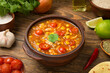 Easy Mexican chicken and rice soup in a terracotta soup bowl on a rustic wooden table with ingredients.