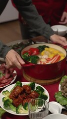 Wall Mural - Vertical Screen: woman grandmother wearing red clothes looking at daughter in law carrying soup on dinner table, getting ready for family reunion meal at home. word on cabinet translation: fortune