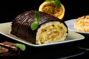 Wall Mural - passion fruit rocambole with chocolate cream icing, black reflective background