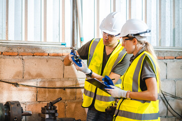 Wall Mural - Female engineer using laptop computer for safety control checks or manufacturing maintenance work in factory building or construction site. woman engineer inspector working in industry product line