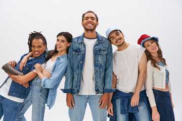 Wall Mural - cheerful multiethnic friends posing near african american man standing with closed eyes on grey