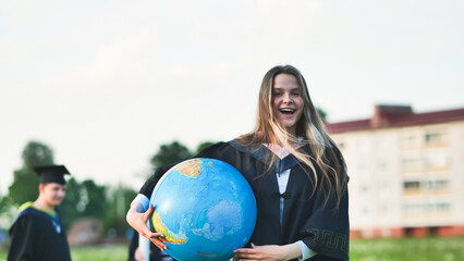 Wall Mural - A graduate student poses with a globe in front of her friends.