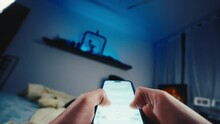 Wide pov shot person typing on smartphone touchscreen laying in bed at night
