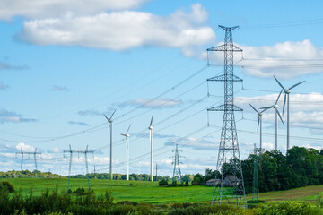 An industrial nature landscape with many high voltage power lines pylons and wind generators