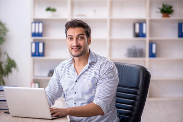 Wall Mural - Young male employee working in the office