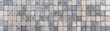 Gehweg aus viereckigen Pflastersteinen in verschiedenen beige und grau Farbtönen in Panorama Nahaufnahme