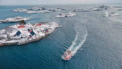 Wall Mural - aerial view of floating fishing boat in blue sea in snowy henningsvaer village, lofoten islands, nor