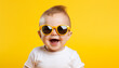 © patternforstock - Funny baby boy wearing big sunglasess isolated on yellow background