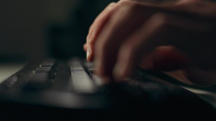 Workflow of a man at a table with a laptop computer, hands deftly moving on the keyboard, forming program code under dim lights. IT specialist in conditions of remote work or distance learning