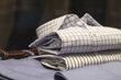 camisas sociais masculinas dobradas de cores claras sobre calca e cinto de couro em closet organizado.