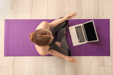 Canvas Print - Sporty young woman with laptop doing yoga in gym, top view