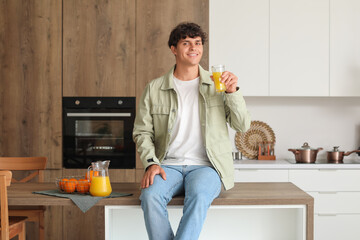 Wall Mural - Young man with glass of orange juice in kitchen