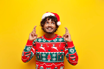 young indian man in new year clothes waiting and hoping with fingers crossed on yellow isolated background