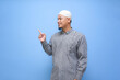 © Iwankrwn - Asian Muslim man pointing finger at free space place for an advertisement isolated on blue background. islamic ads concept