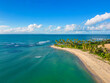 Aerial panoramic view of wild beach with green palm trees on the shore. Beautiful landscape with blue sky and turquoise sea water. Best places for summer vacations