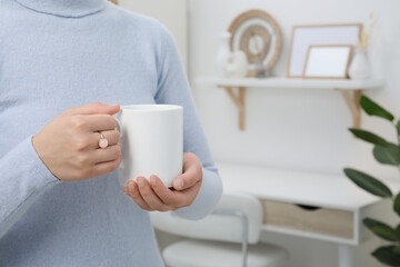 Sticker - Woman holding white mug at home, closeup and space for text. Mockup for design