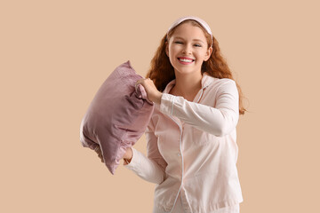 Happy young woman with pink soft pillow on beige background