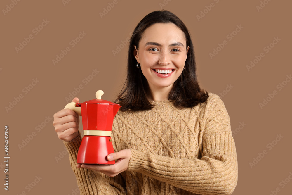 Pretty young woman with geyser coffee maker on brown background