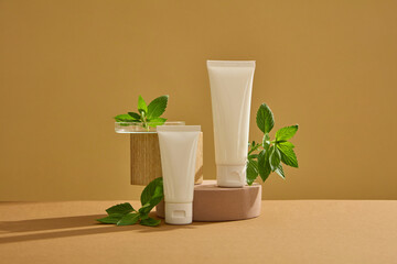 Sticker - Mockup scene for advertising and branding cosmetic of spearmint ingredient. White plastic tubes displayed on brown background with fresh spearmint leaves. Mockup for advertising