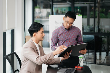 Businessman leading team meeting and using tablet and laptop computer with financial in co working office