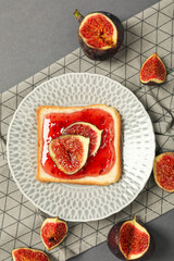 Sticker - Piece of bread with jam and figs on plate on gray background, top view