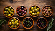 Assortment of fresh olives with different colors in bowls with rosemary branches on wooden background. Top view.