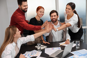 Wall Mural - Team of employees joining hands in office