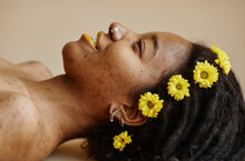 Woman With Yellow Flowers On Hair Against Brown Background
