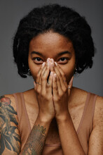 Young Woman Covering Face With Hands Against Gray Background
