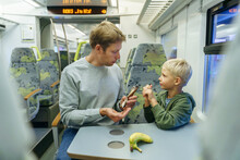 Father And Son Having Banana In Train