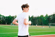 © Westend61 - Teenage boy running in stadium under sky