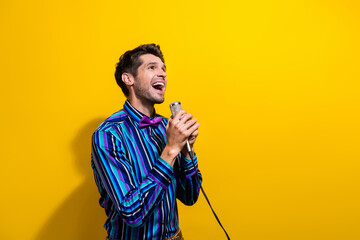 Poster - Photo of stylish man dressed striped shirt bow tie sing song in microphone look up empty space isolated on yellow color background