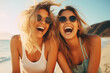 © koala studio - Portrait of two happy young women in sunglasses having fun on the beach