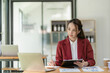© ArLawKa - Asian businesswoman working using laptop computer calculating expenses, financial report making note paper Data sheet, graph and laptop