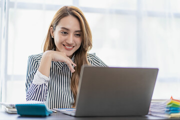 Wall Mural - Asian businesswoman working using laptop computer calculating expenses, financial report making note paper Data sheet, graph and laptop