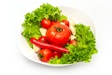 Wall Mural - Delicious vegetable salad in a bowl with water drops. Tomatoes, lettuce, garlic, chili.