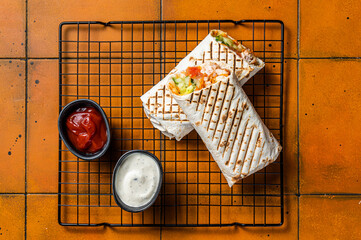 Wall Mural - Shawarma durum doner kebab with meat and vegetable salad. Orange background. Top view