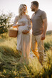 Beautiful young pregnant couple spending time together in outdoor at sunset. The concept of expecting a baby, parenthood.