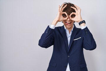 Poster - Hispanic business young man wearing glasses doing ok gesture like binoculars sticking tongue out, eyes looking through fingers. crazy expression.