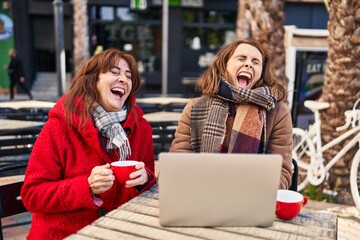 Canvas Print - Two women mother and daughter using laptop drinking coffee at coffee shop terrace